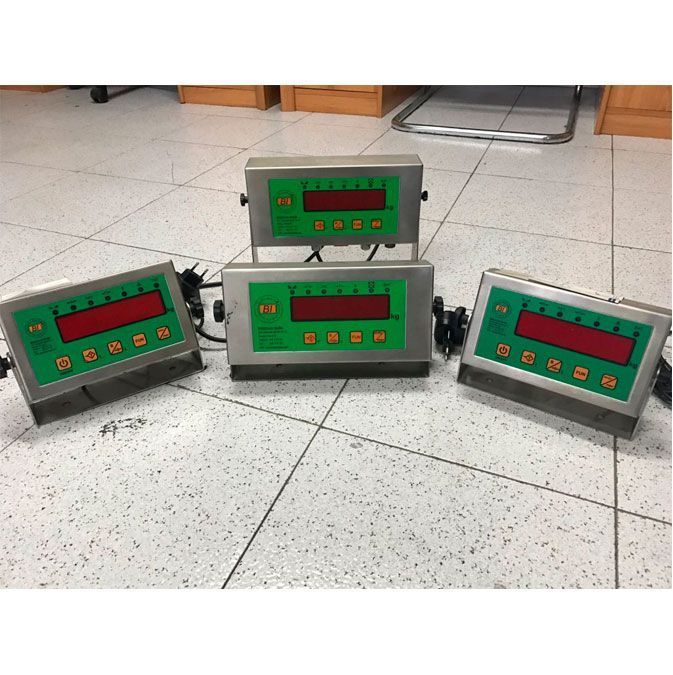 Tres básculas digitales están sobre un suelo de baldosas.