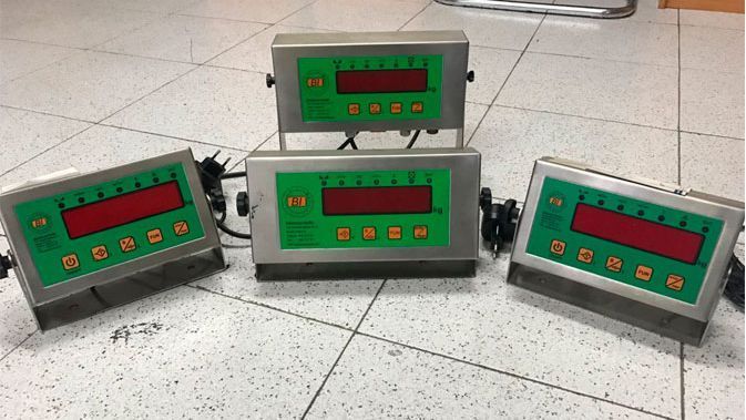 Tres básculas digitales están apiladas una encima de otra sobre un suelo de baldosas.