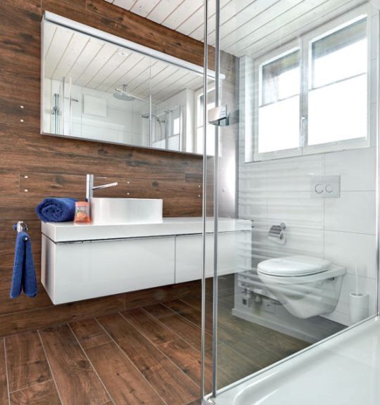 Ein Badezimmer mit Fliesen, Toilette, Waschbecken und Spiegel. Foto von der Reto Wicki GmbH
