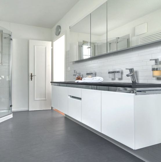 Ein Badezimmer mit weissen Schränken und Keramikplatten. Foto von der Reto Wicki GmbH