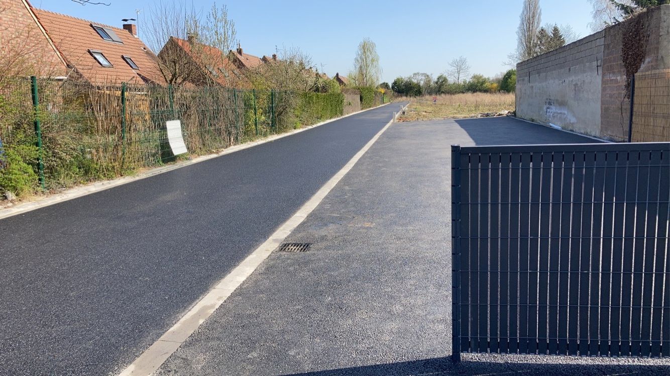 Enrobés sur une route devant des habitations
