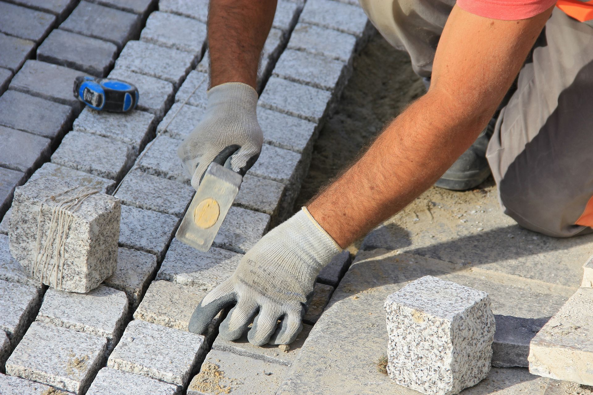 Professionnel tapant au marteau sur des pavés installés à la main