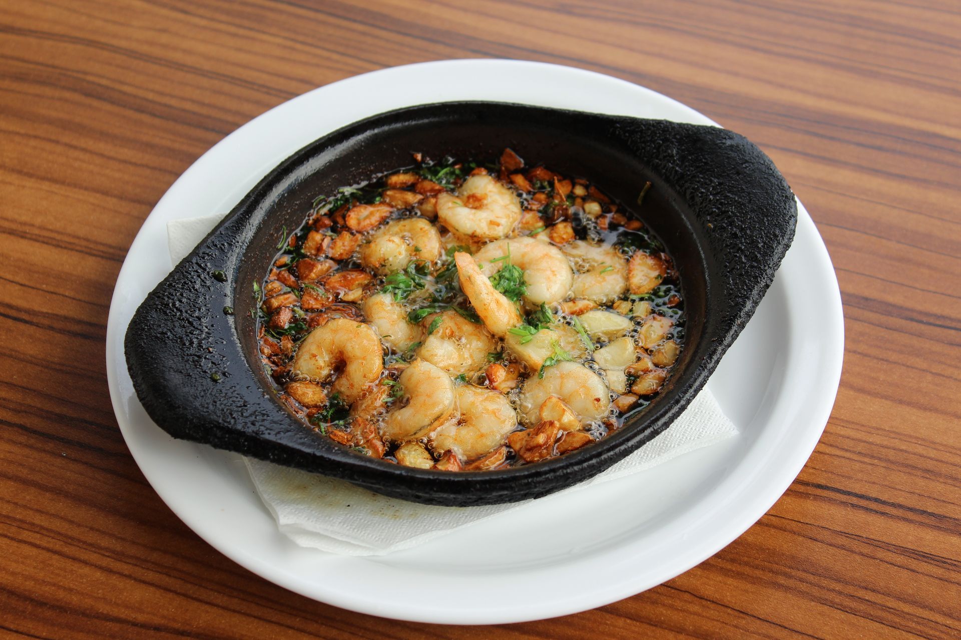 Plato de calamares fritos y patatas fritas, y un plato de camarones al ajillo.
