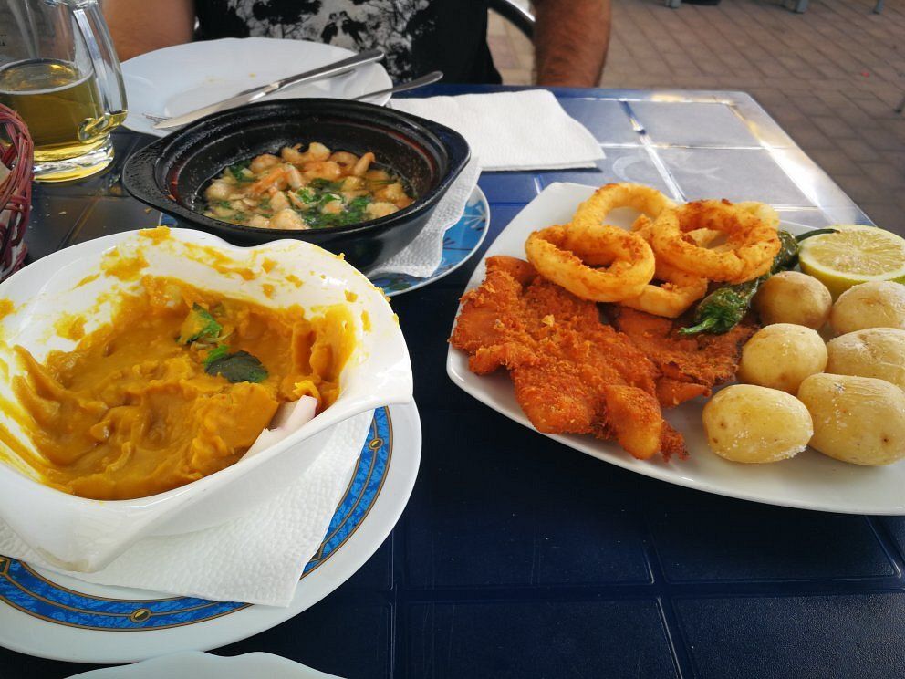 Plato de comida frita con patatas, calabaza y guiso de frijoles sobre una mesa.