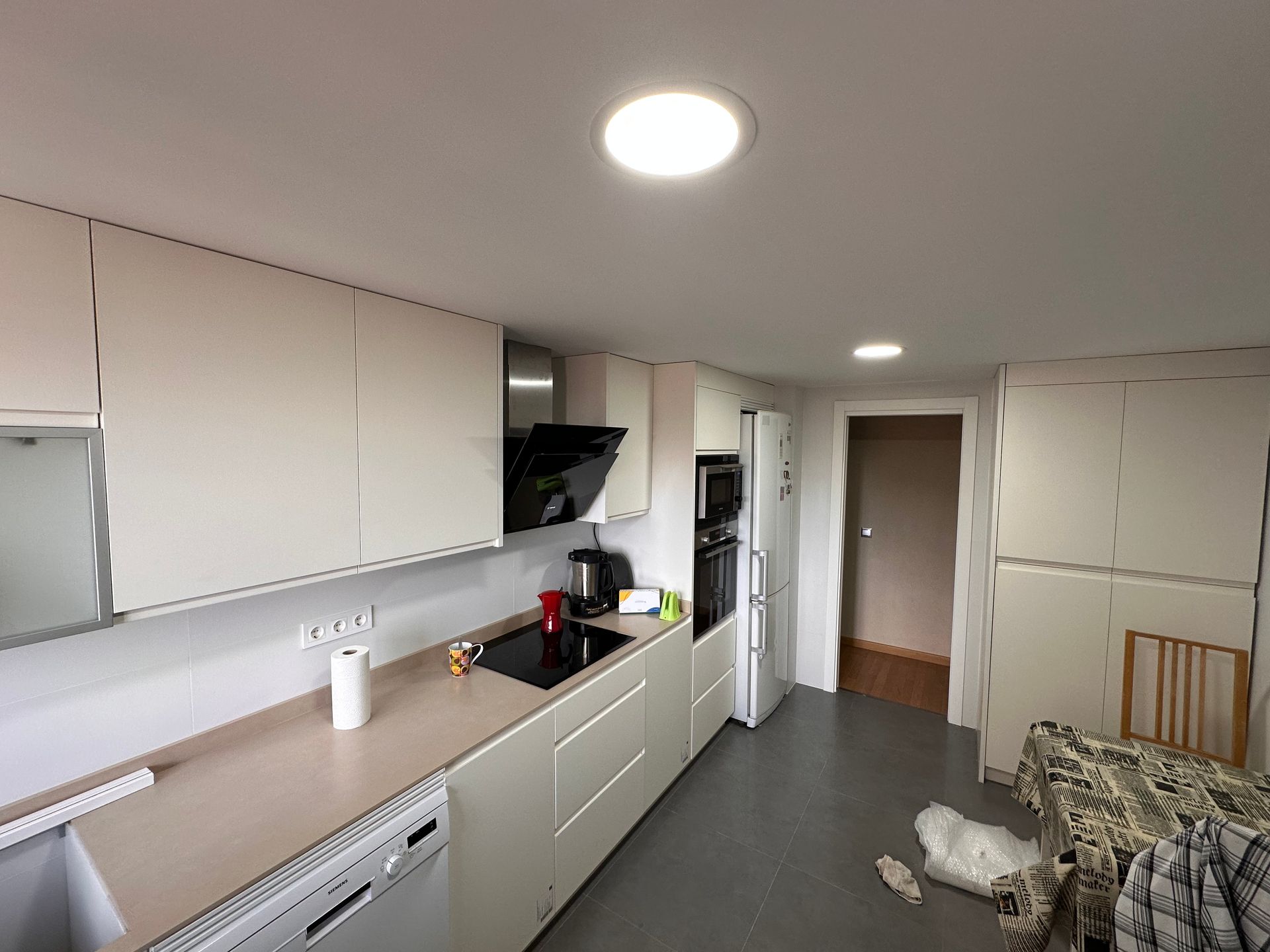 Cocina moderna con gabinetes blancos, encimera clara y electrodomésticos negros.