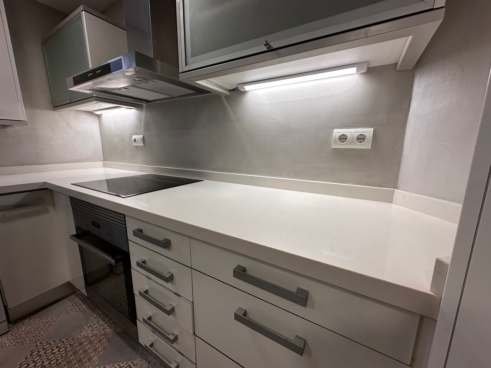 Cocina blanca moderna con encimeras, gabinetes y electrodomésticos.