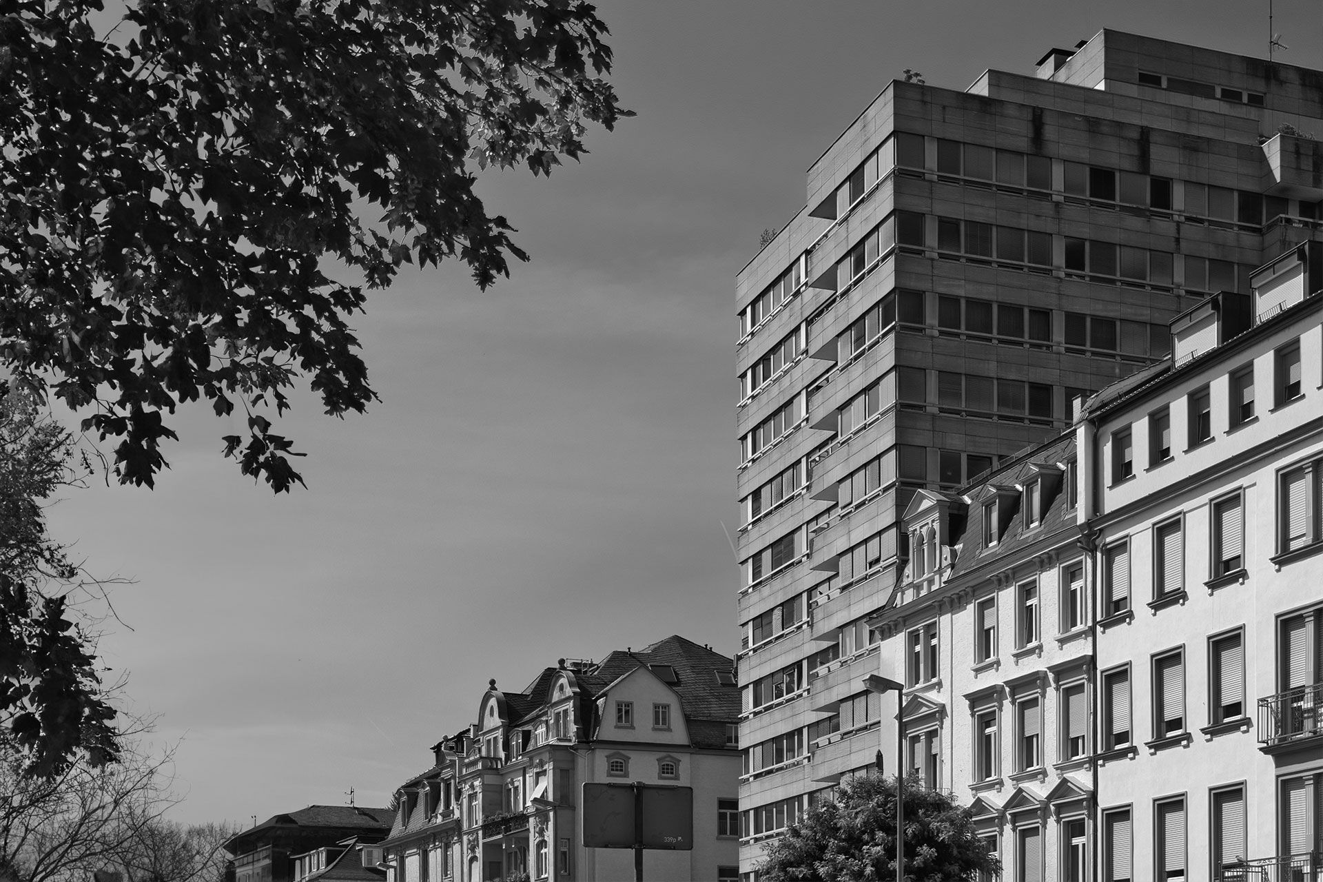 Ein Schwarzweißfoto einer Gebäudereihe mit Bäumen im Vordergrund.