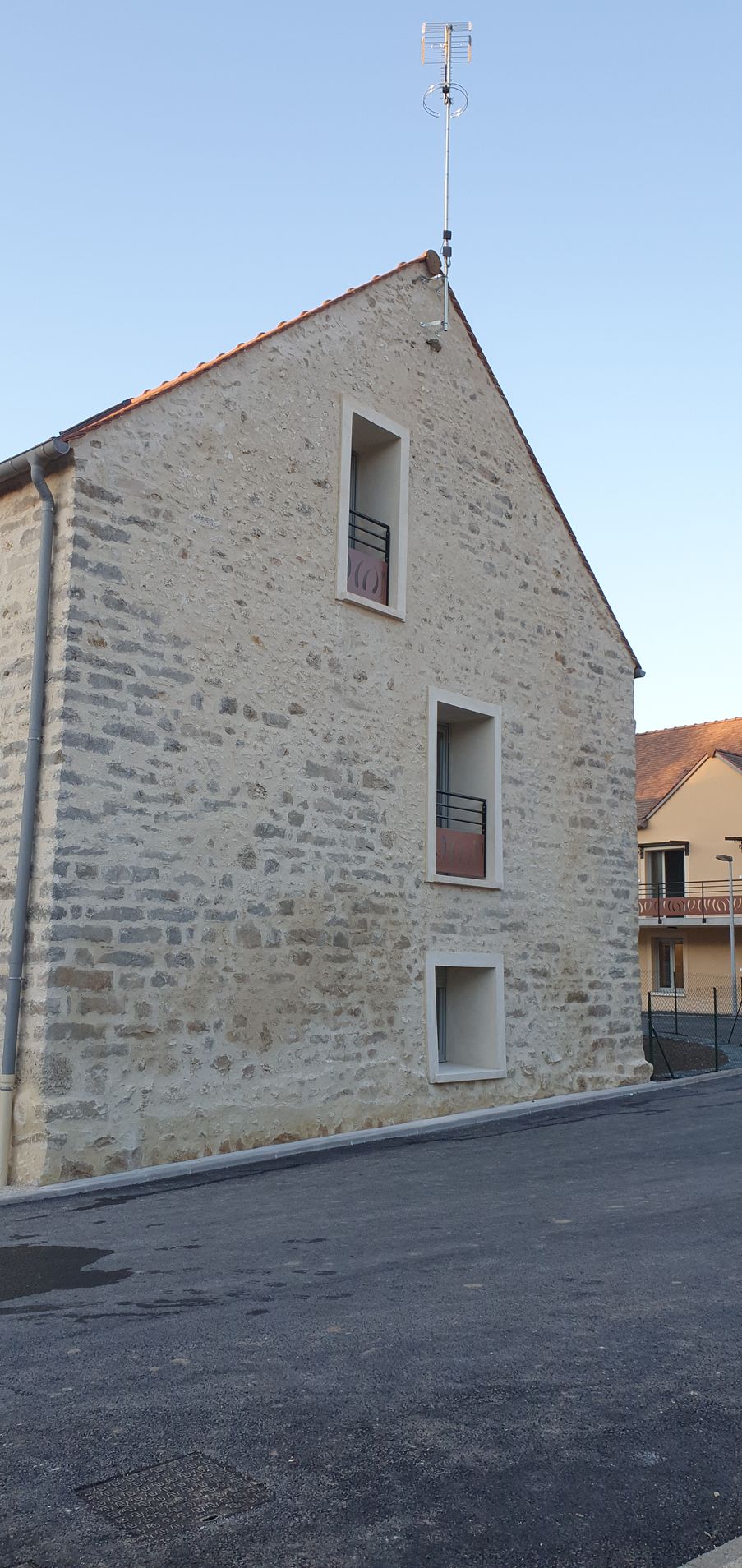 Maison en pierre avec un toit à pignon abrupt et de petites fenêtres donnant sur une rue pavée