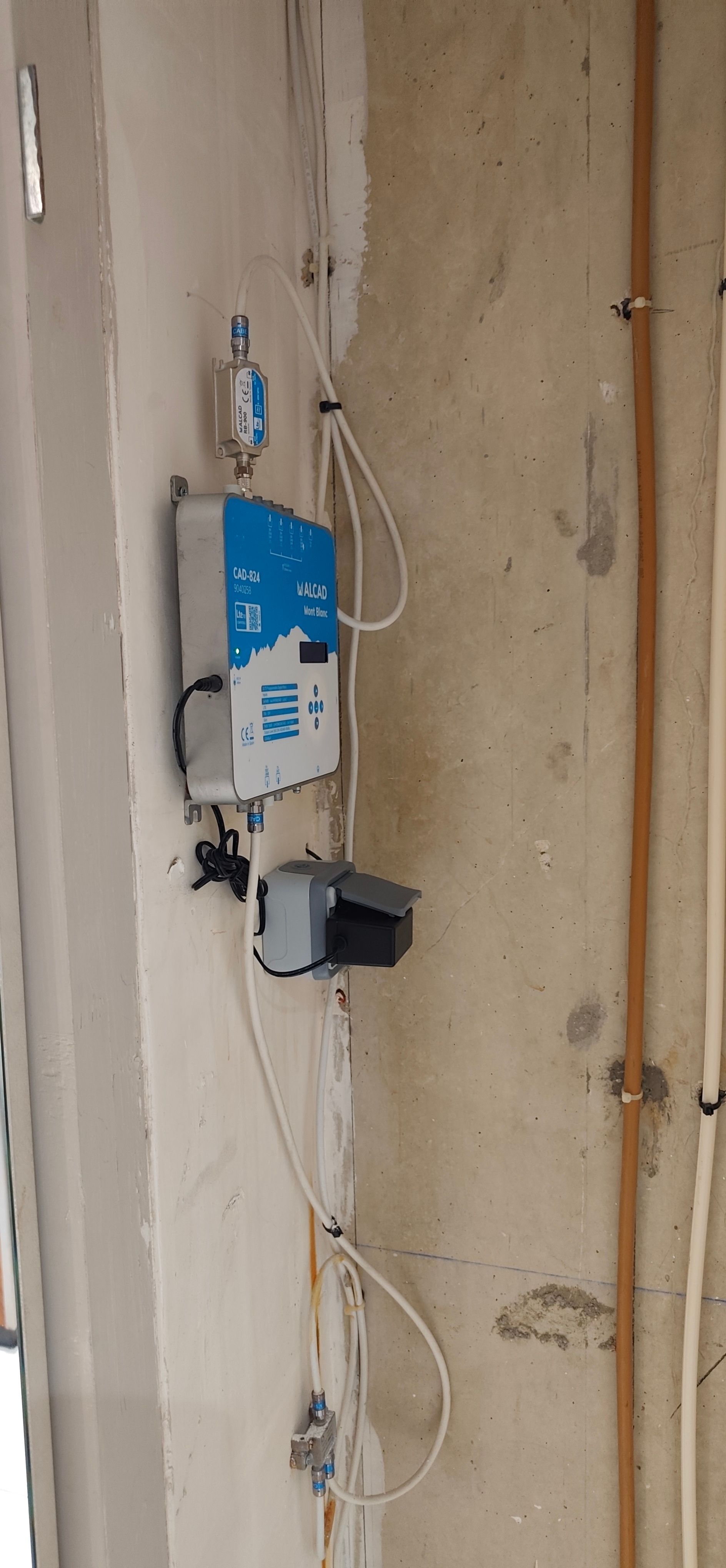 Dispositif électrique mural bleu et blanc avec fils fixés dans un mur intérieur nu