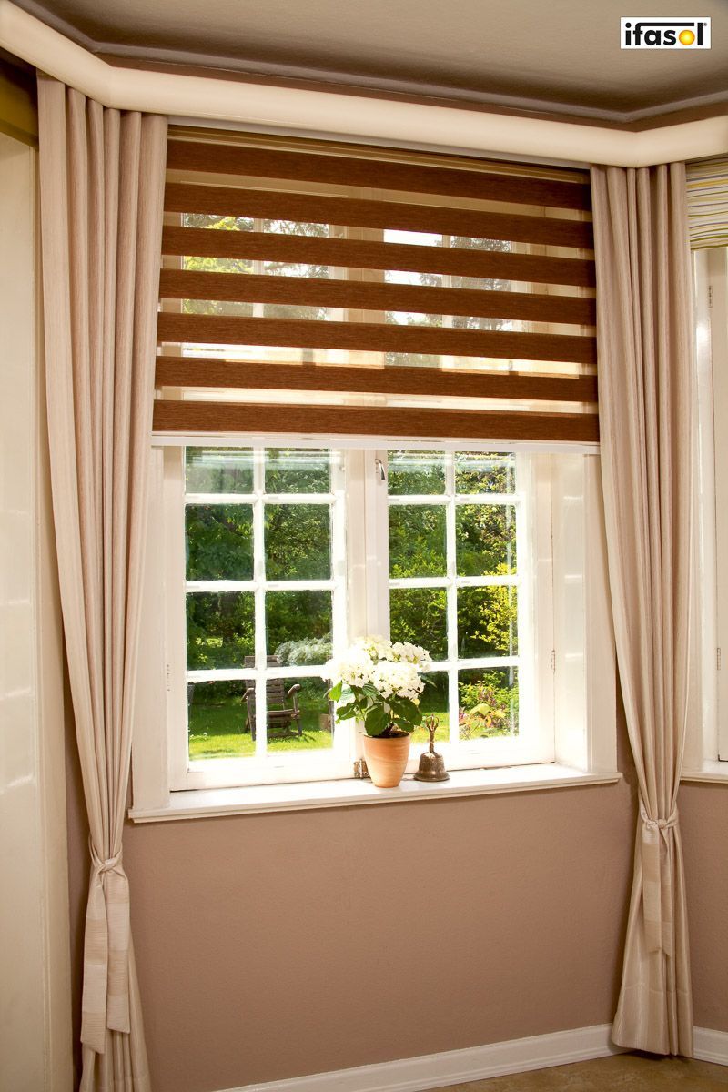 ein Wohnzimmer mit einem Fenster und einer Pflanze auf der Fensterbank - Sonnenschutz von Gardinen Breuß aus Elmshorn