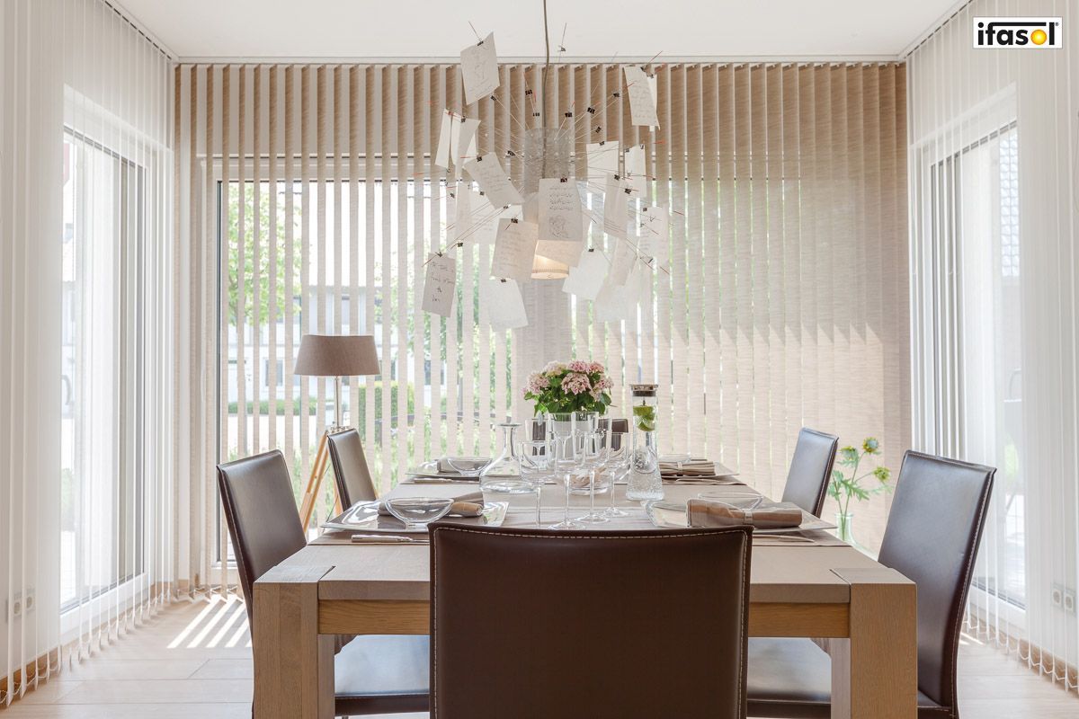 ein Esszimmer mit einem Tisch und Stühlen und vielen Fenstern - Sonnenschutz von Gardinen Breuß aus Elmshorn