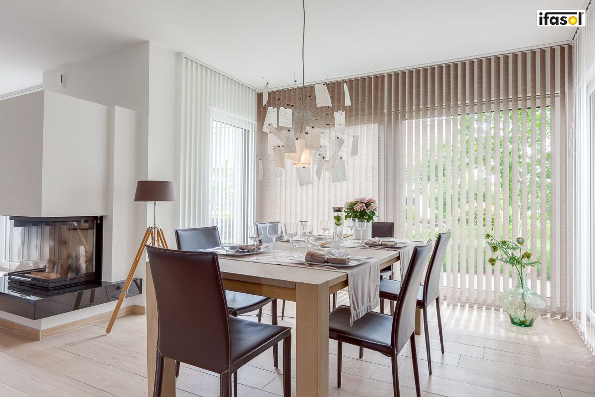 ein Esszimmer mit einem Tisch und Stühlen und einem Kamin - Sonnenschutz von Gardinen Breuß aus Elmshorn