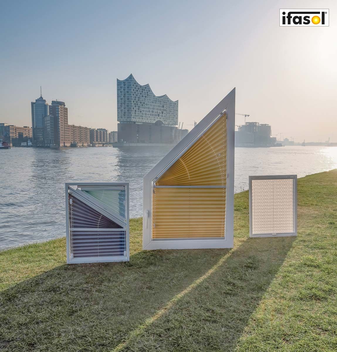 drei Fensterläden stehen auf einer Wiese neben einem Fluss - Sonnenschutz von Gardinen Breuß aus Elmshorn