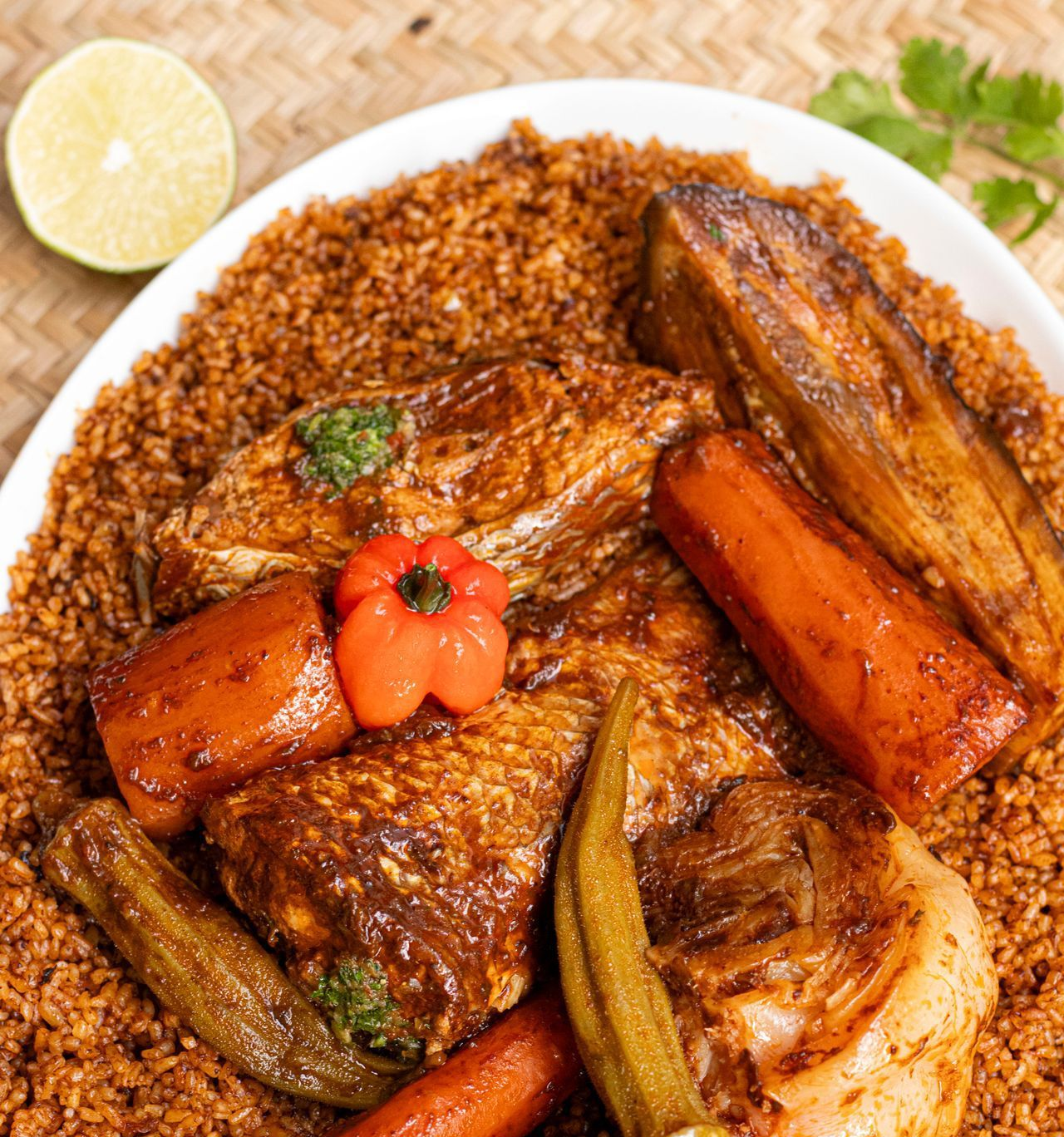 Assiette de thiéboudiène : riz, poisson, légumes (aubergine, carottes, gombo), poivron rouge, citron vert.