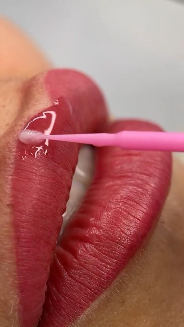 Un primer plano de los labios de una mujer con un pincel rosa.