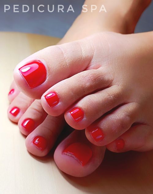 Un primer plano de los pies de una persona con uñas rojas.