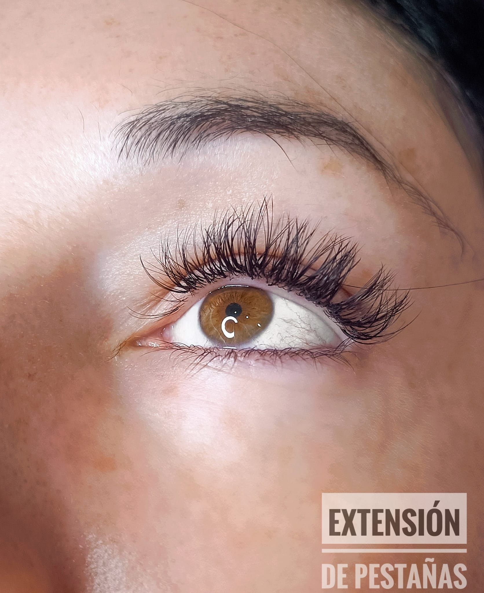 Un primer plano del ojo de una mujer con extensión de pestañas escrita en la parte inferior.