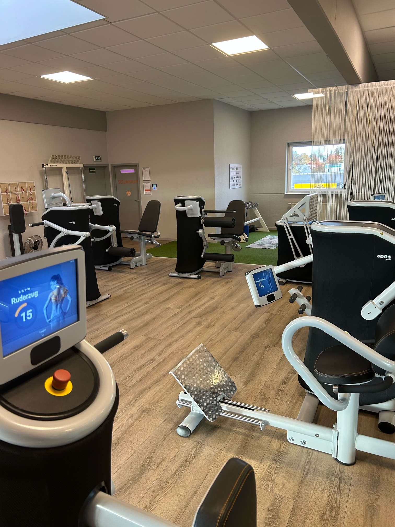 Ein Fitnessstudio mit vielen Trainingsgeräten und einem Monitor.