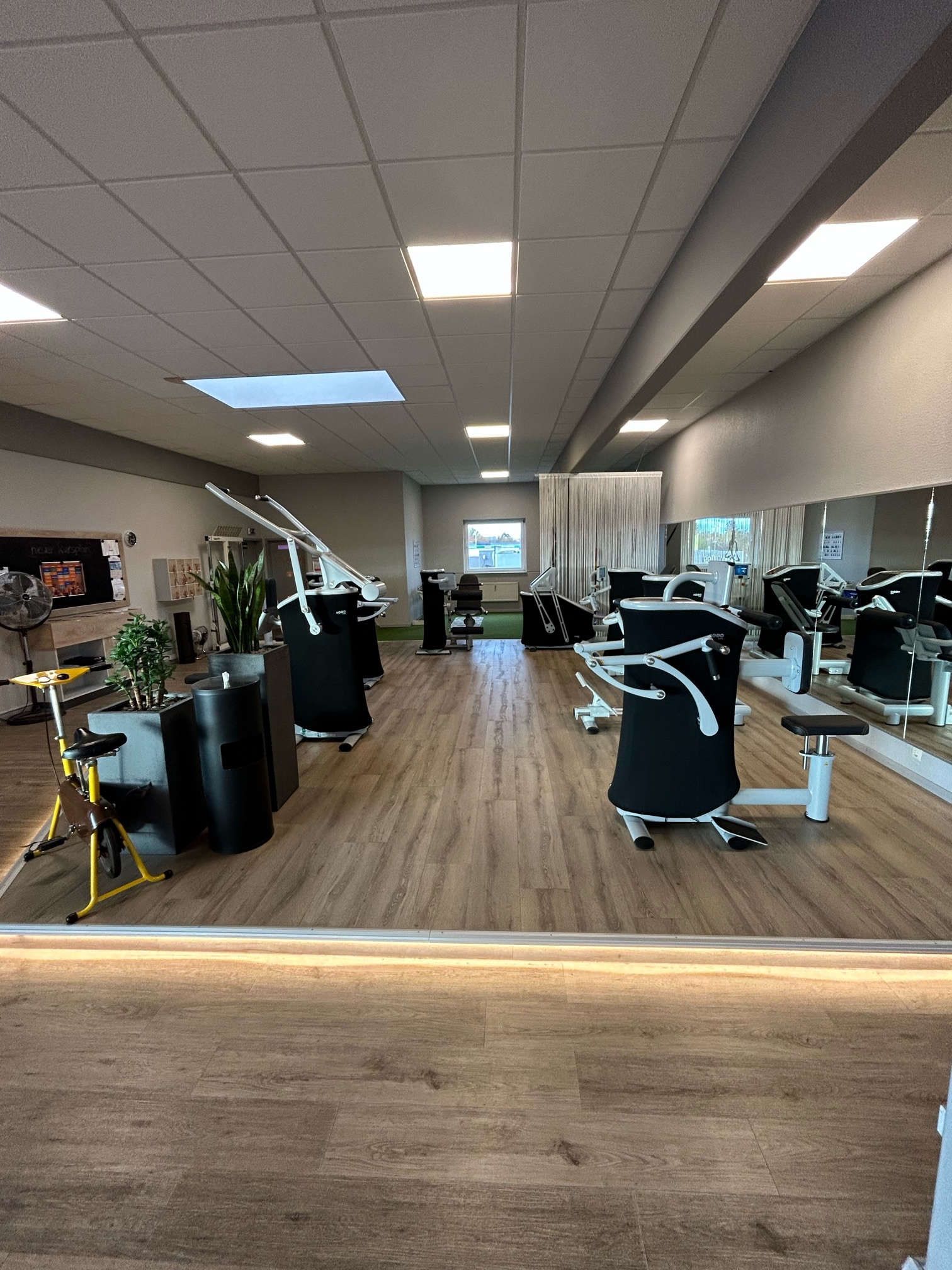 Ein Fitnessraum mit vielen Trainingsgeräten und einem großen Spiegel.