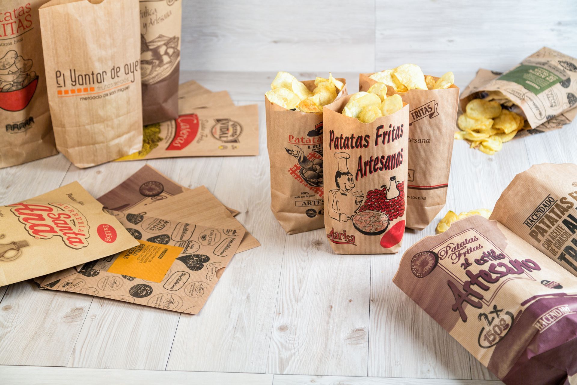 Un montón de bolsas de papel llenas de papas fritas están sobre una mesa.