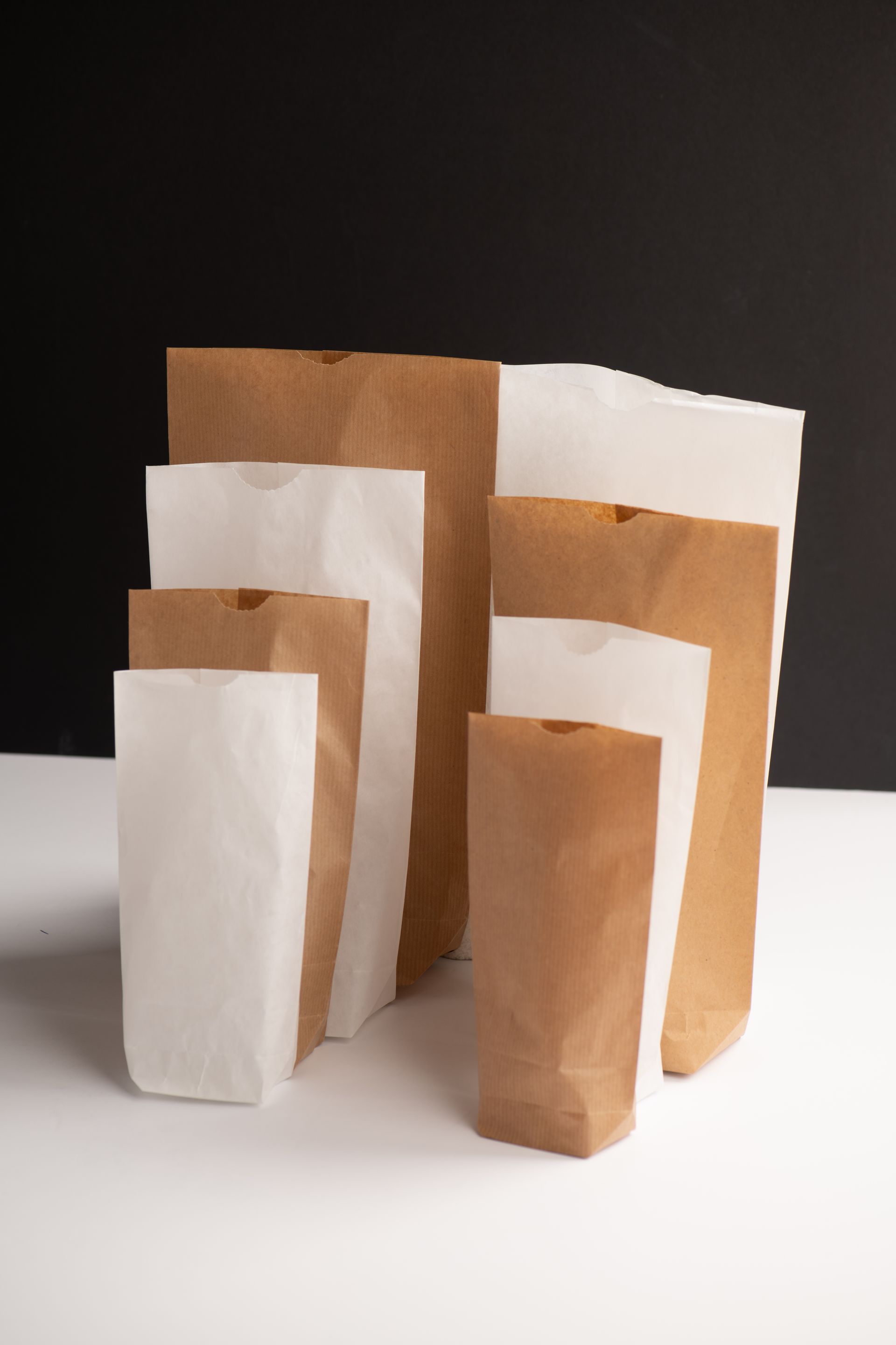 Un grupo de bolsas de papel marrones y blancas están apiladas una encima de otra sobre una mesa.