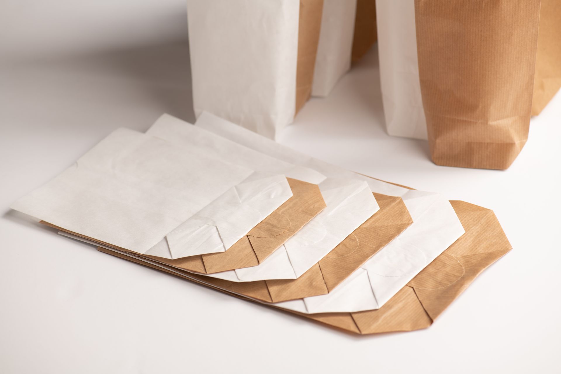 Una pila de bolsas de papel marrones y blancas sobre una mesa.