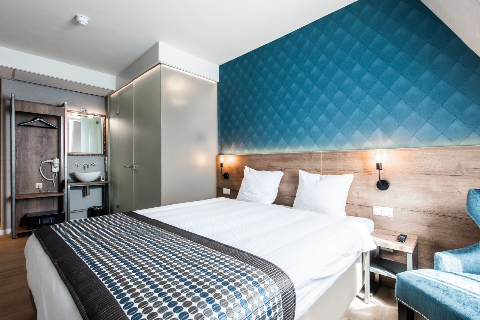 A hotel room with a bed , chair and sink.