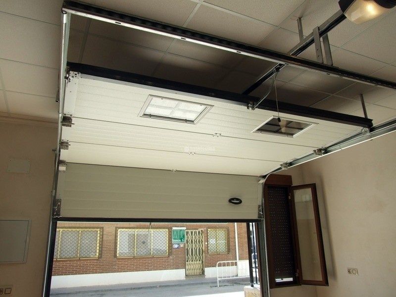 Una puerta de garaje seccional de color crema, parcialmente abierta