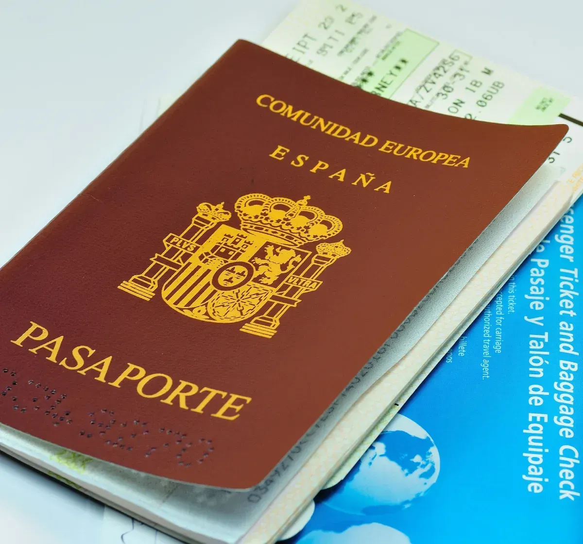 Pasaporte español sobre la tarjeta de embarque y el billete. Pasaporte marrón, emblema dorado