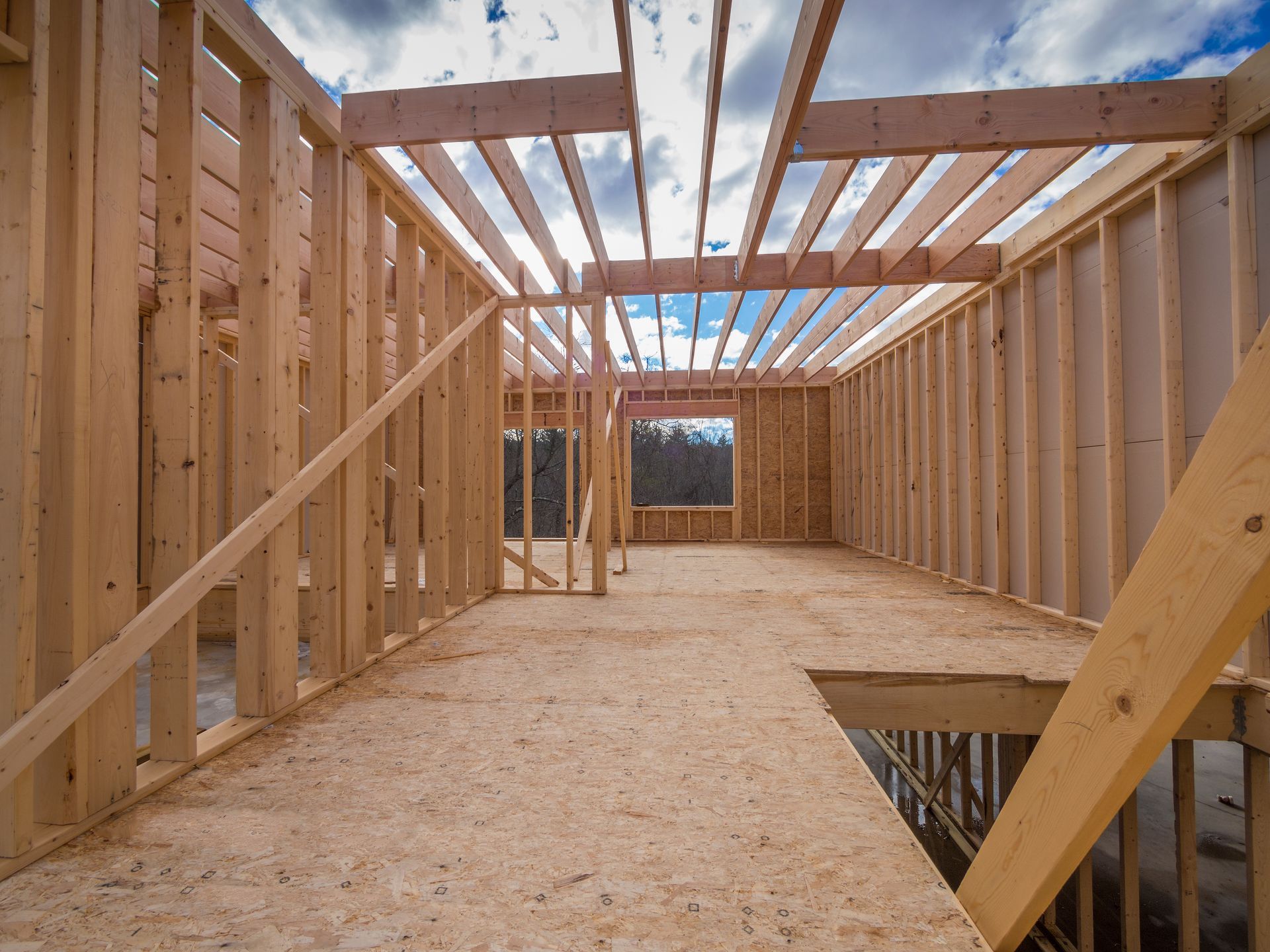 Vue intérieure d'un immeuble résidentiel en construction, montrant la charpente des murs en bois et les solives.