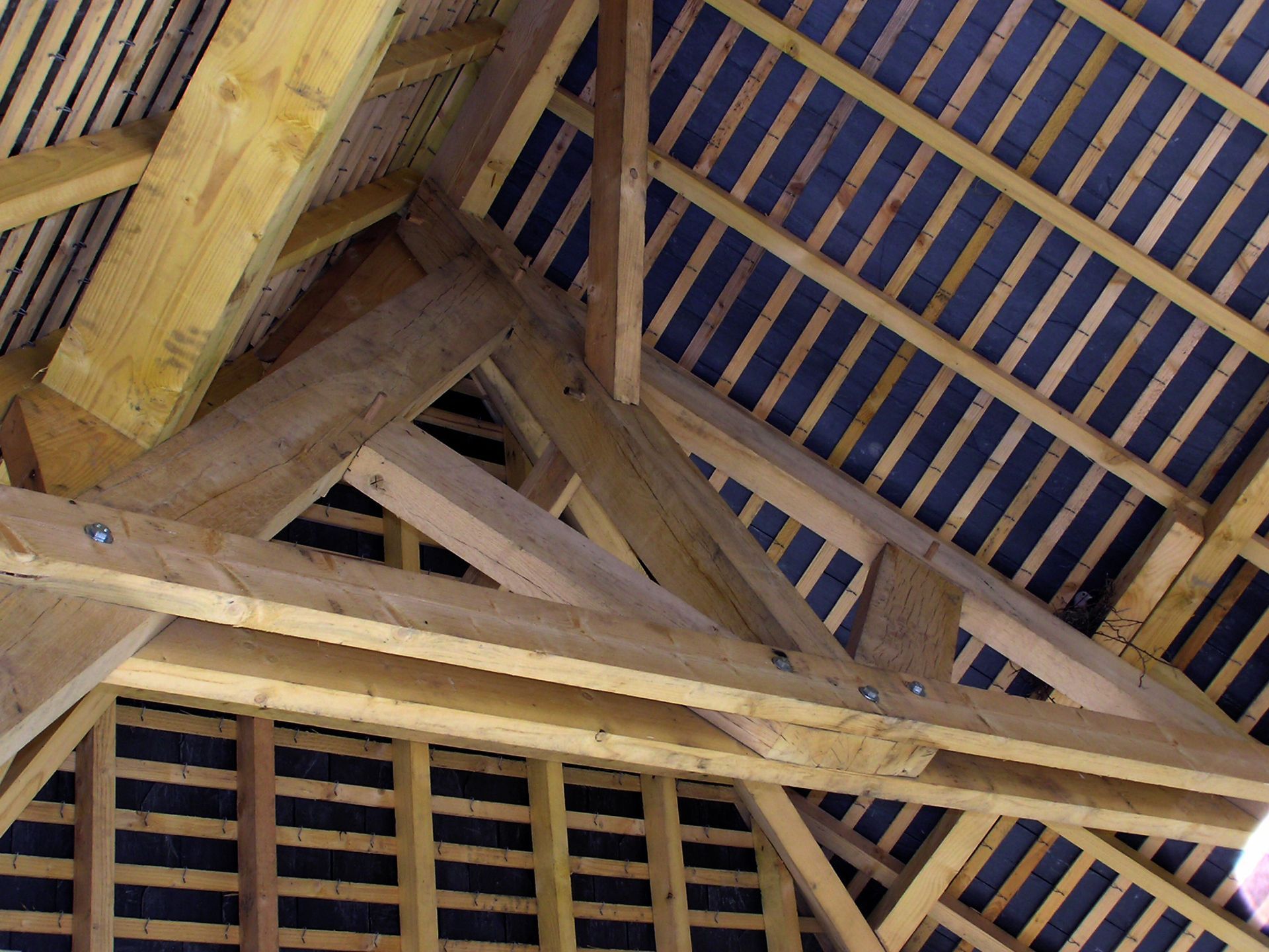 Charpente et chevrons en bois soutenant une structure de toit avec feutre bitumé foncé et liteaux horizontaux.