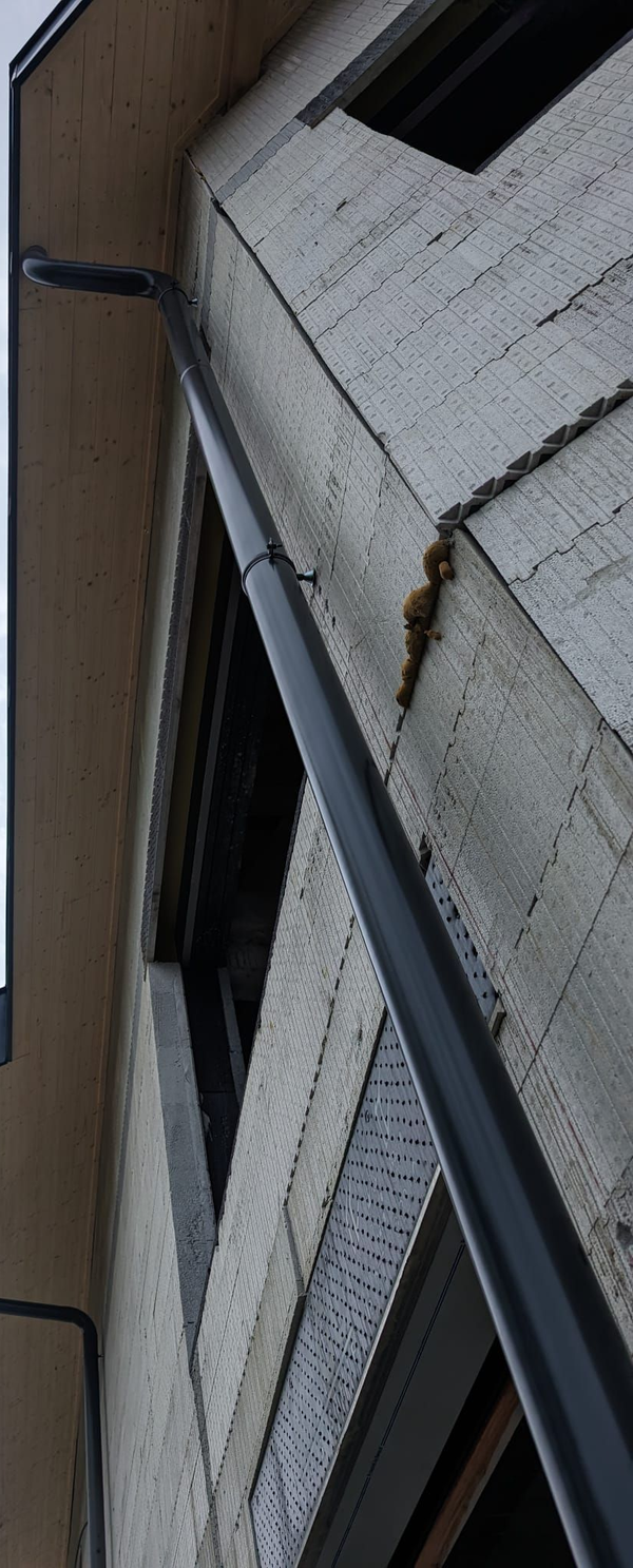 Vue en contre-plongée de deux descentes de gouttière en métal fixées sur le côté d'un mur extérieur et non fini.