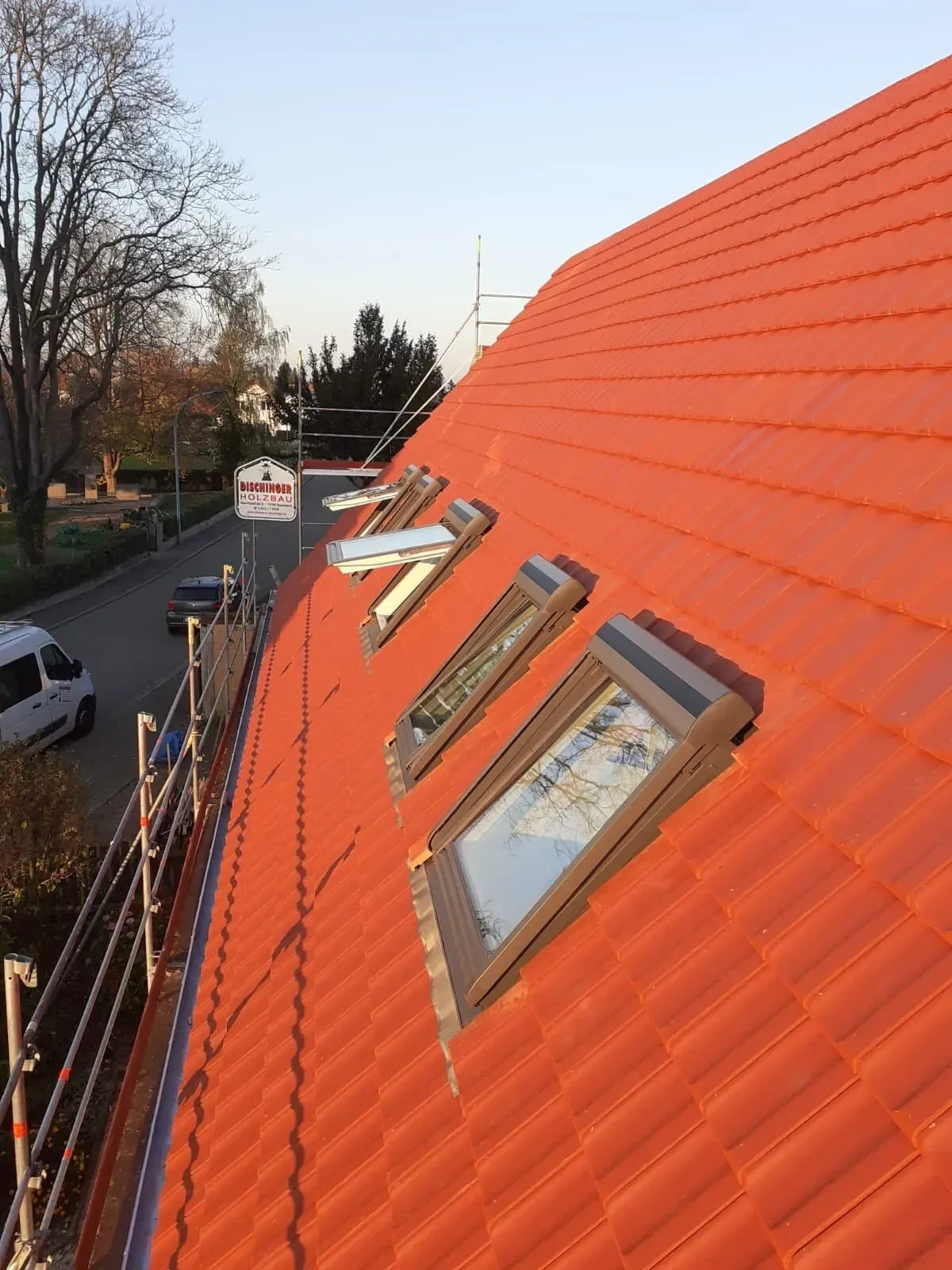 Ein rotes Ziegeldach mit einer Reihe von Oberlichtern darauf.