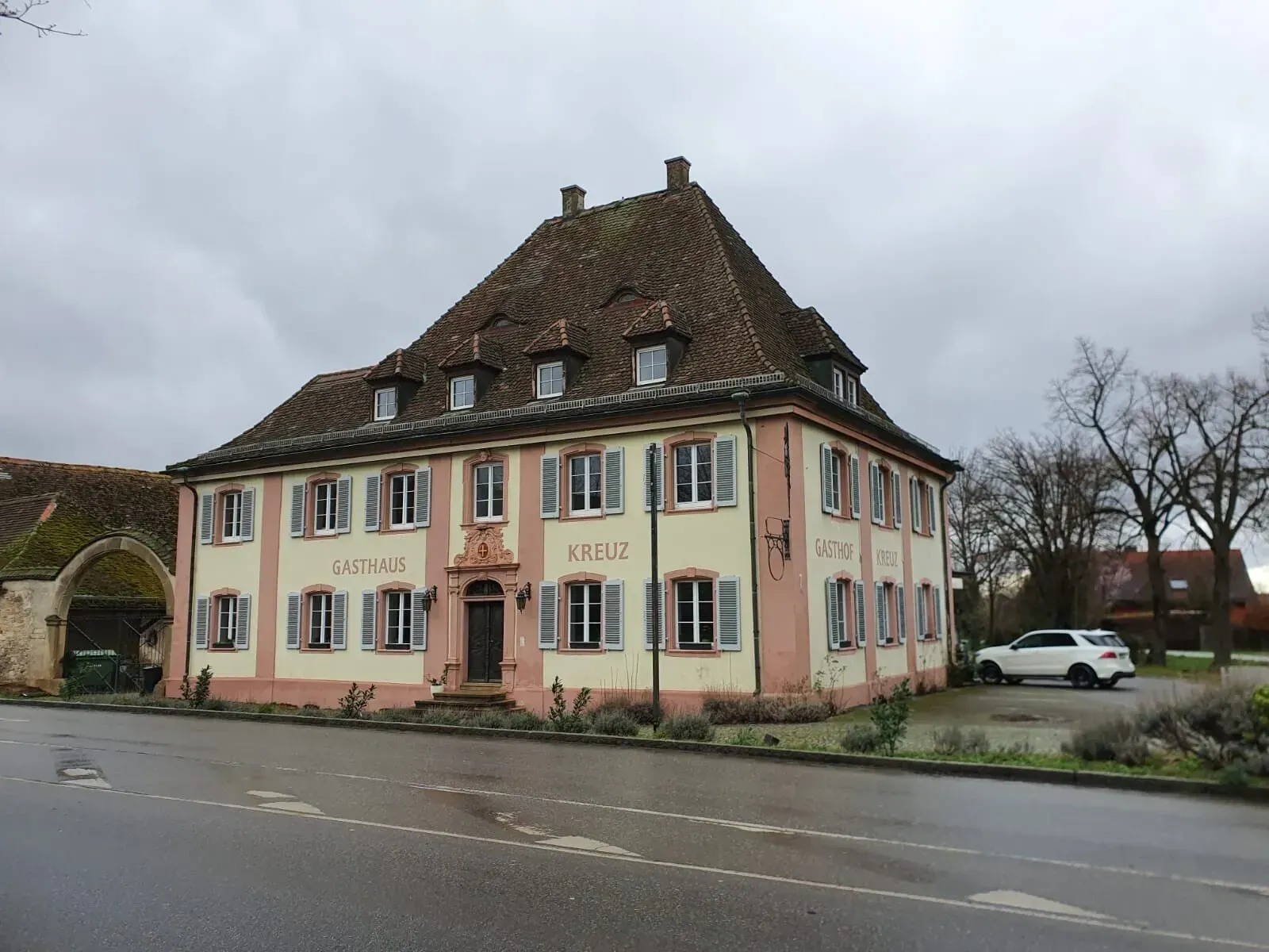 Am Straßenrand steht ein großes Gebäude mit einem Dach und vielen Fenstern.