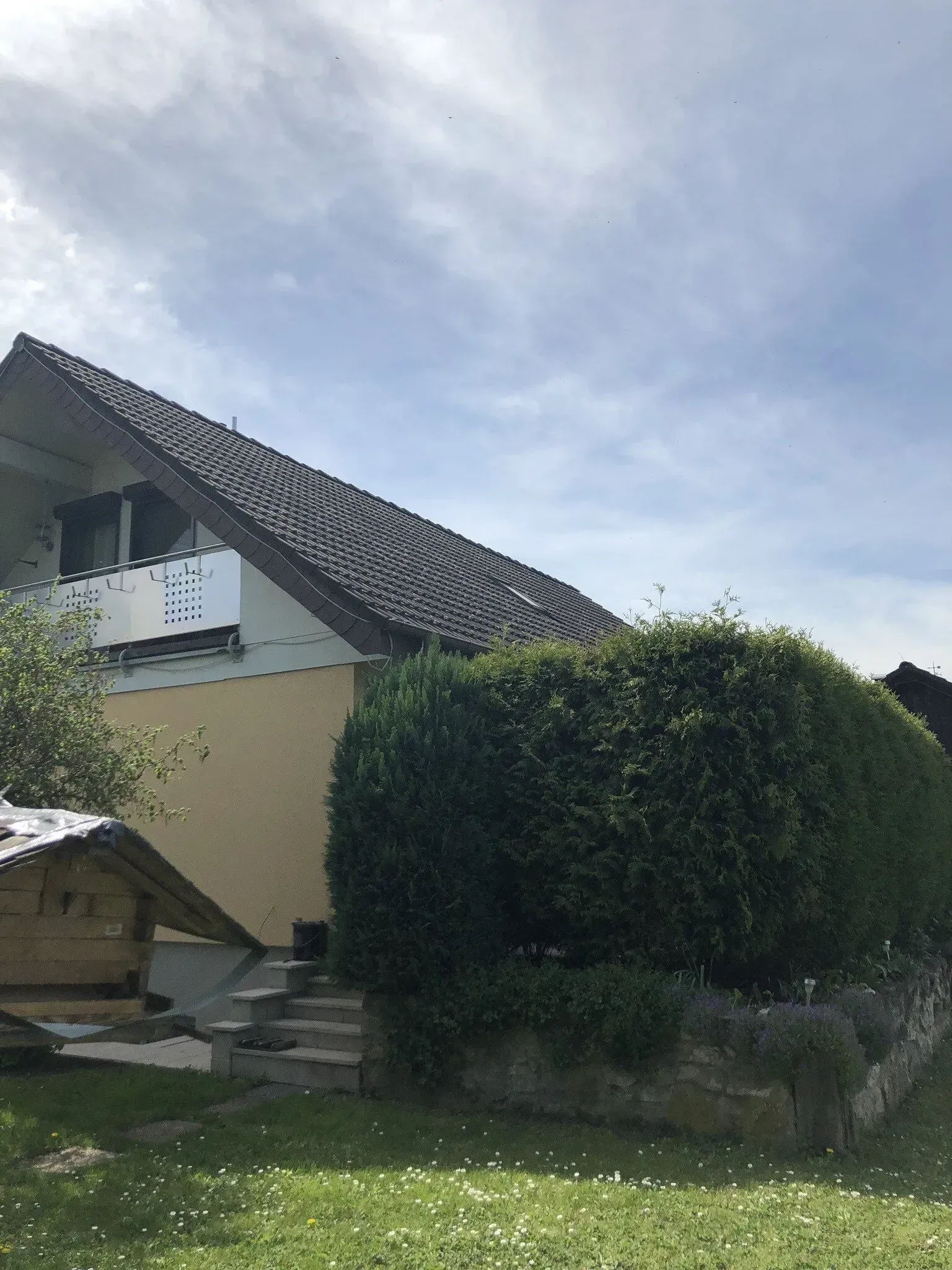 Ein Haus mit Balkon und einer Hecke davor