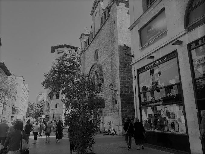 Una fotografía en blanco y negro de personas caminando por una calle frente a un edificio.