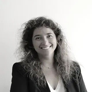 Una mujer con cabello largo y rizado sonríe en una foto en blanco y negro.