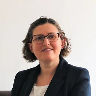 Una mujer que lleva gafas y traje sonríe para la cámara.
