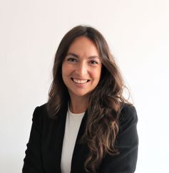 Una mujer con una chaqueta negra y una camisa blanca sonríe a la cámara.