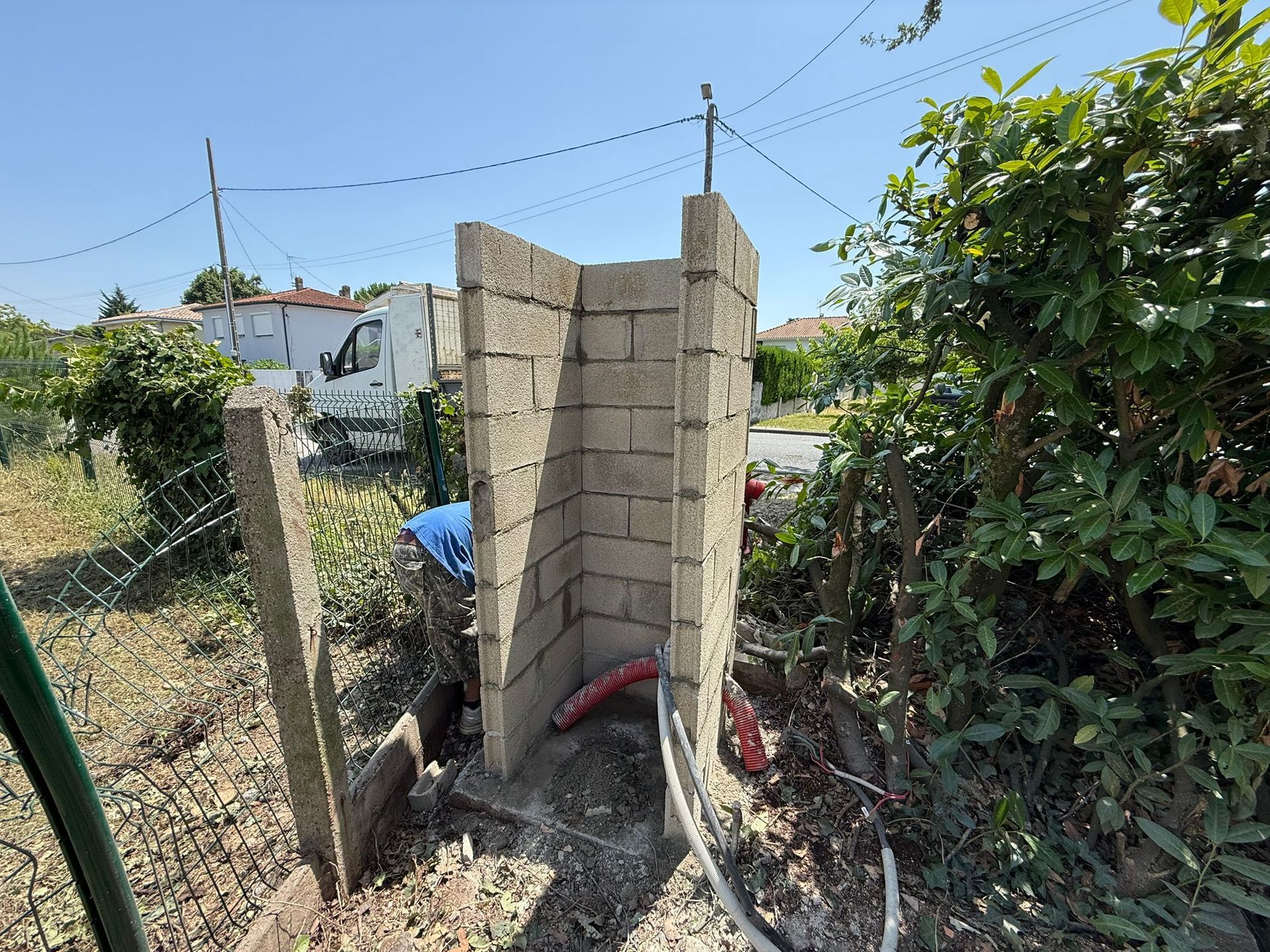 Maçonnerie d'un mur en parpaing béton en cours de construction pour protéger une arrivée d'eau.