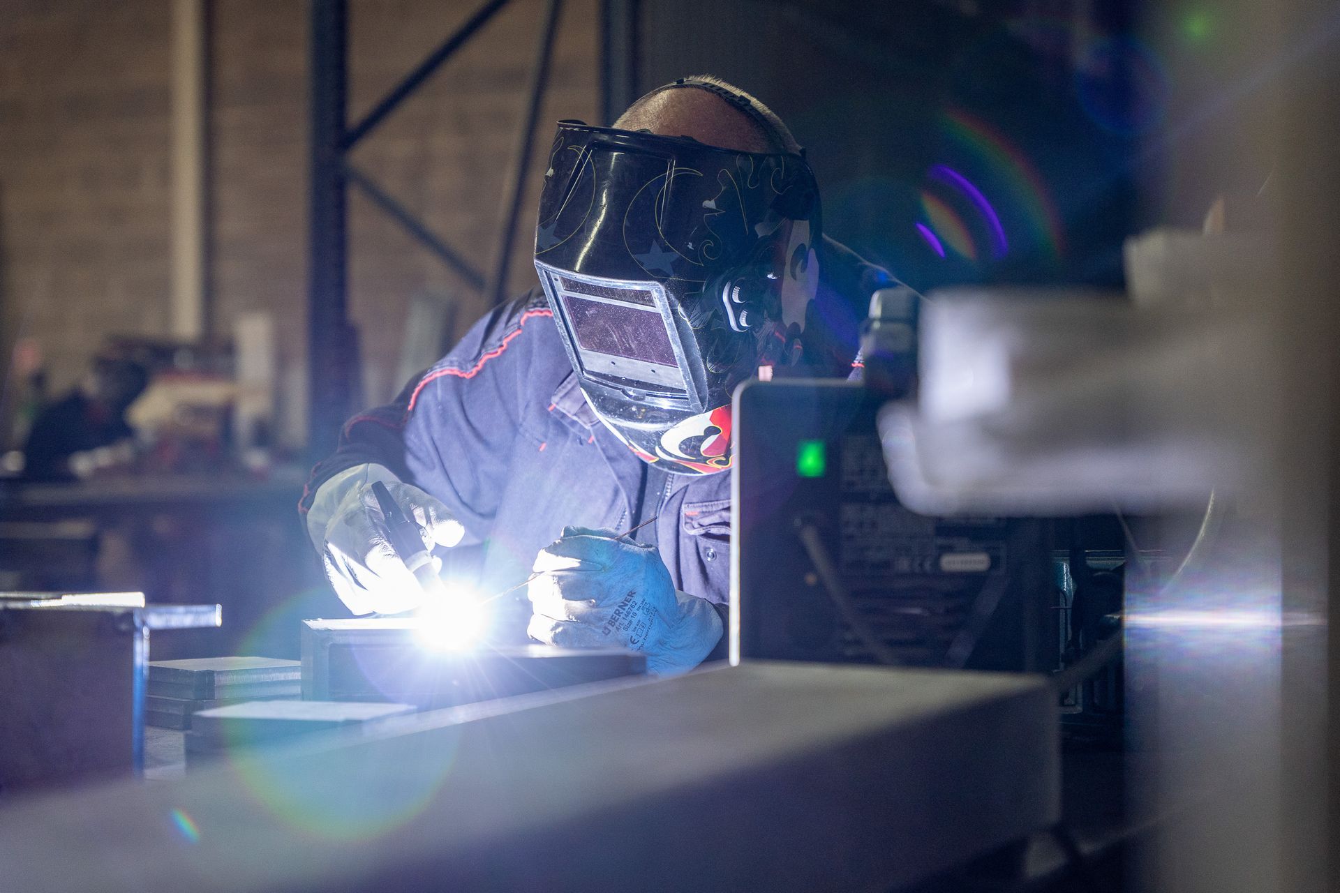 Technicien effectuant une soudure de précision sur du métal, dans un atelier industriel.