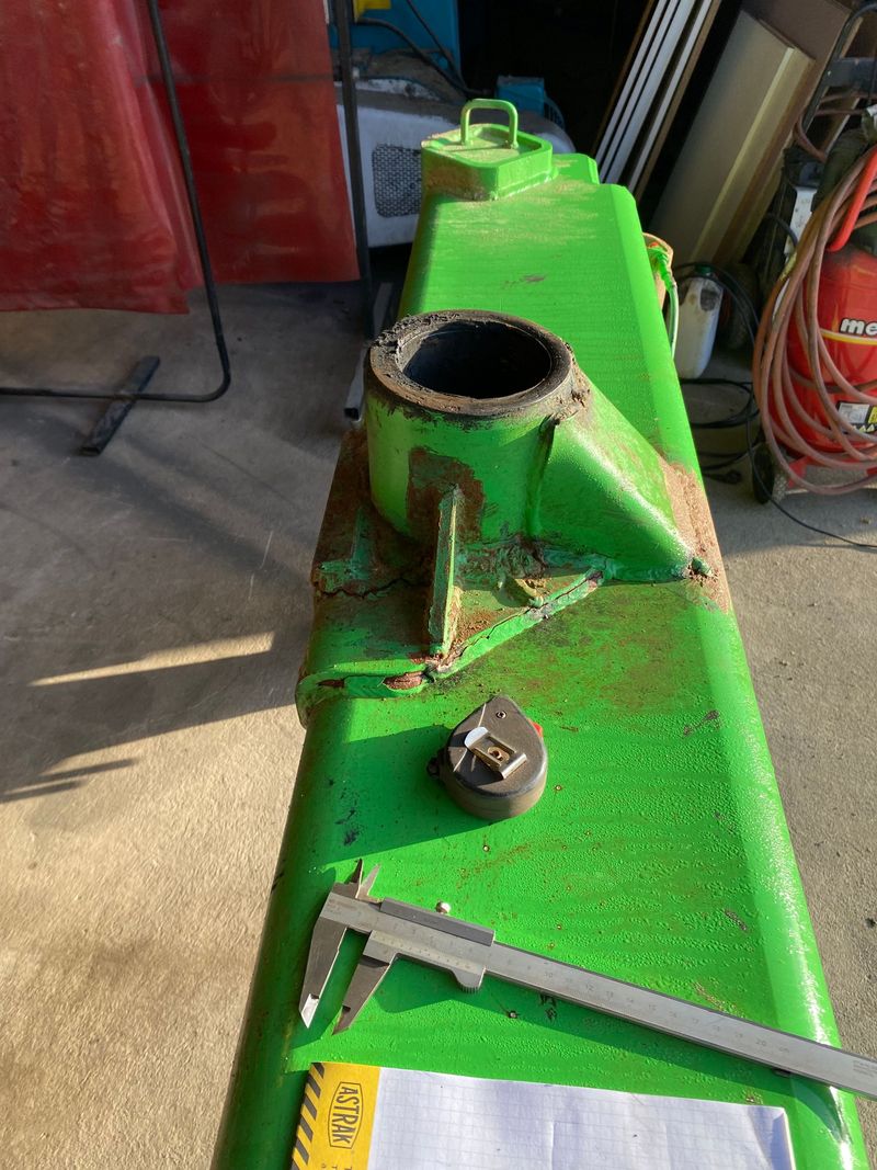 Établi en métal vert avec support cylindrique et traces de rouille.