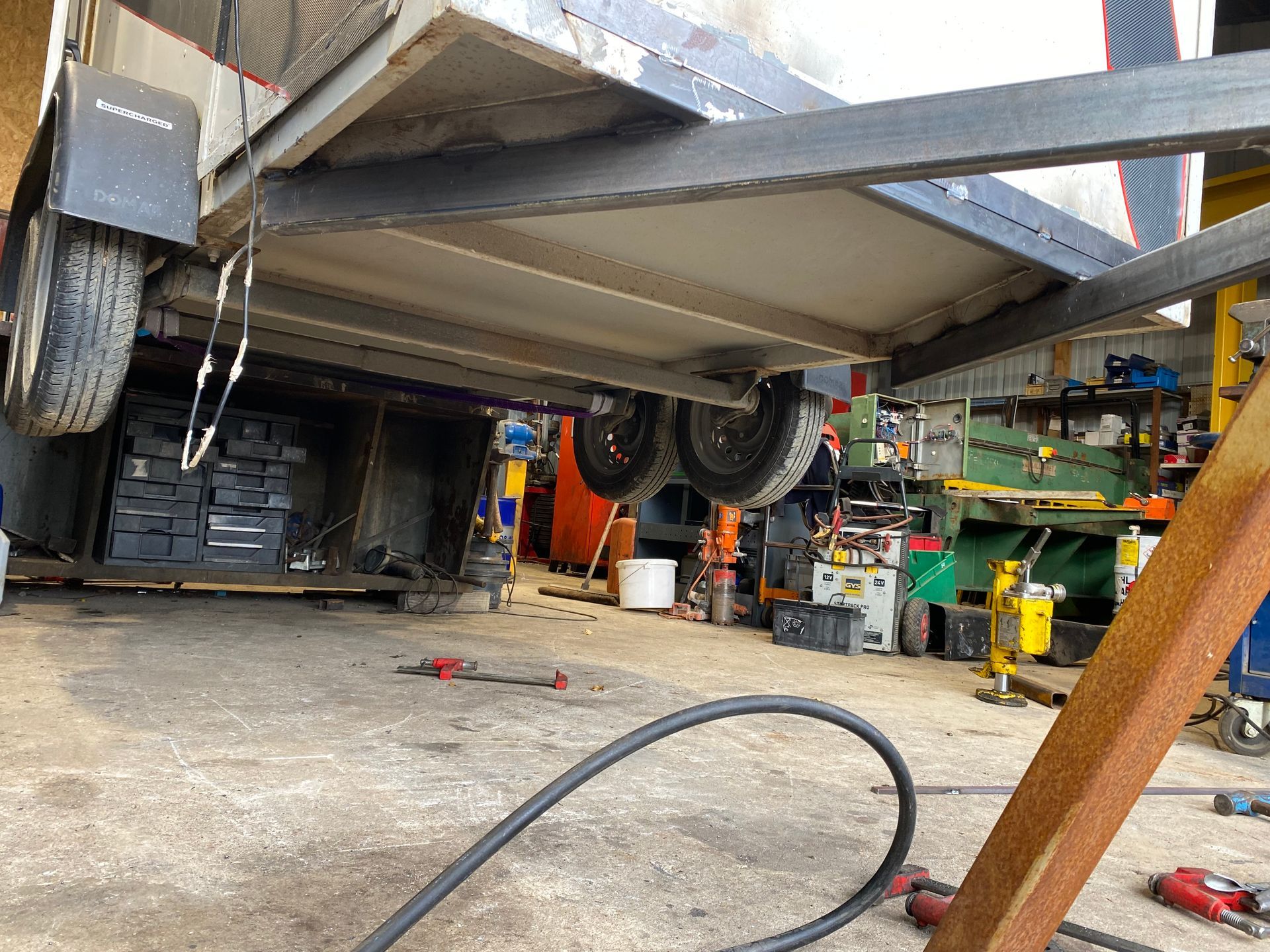 Châssis de remorque soulevé dans un atelier ; vue des roues et de la structure métallique.
