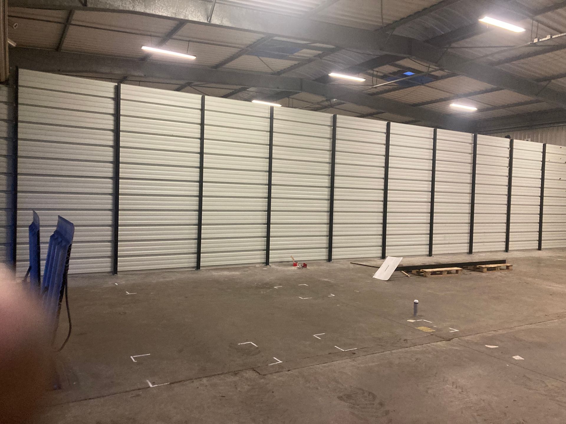 Bardage acier fixé sur une structure métallique intérieure, avec des montants verticaux dans un atelier.
