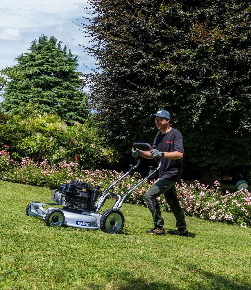 Tondeuse à gazon bleue coupant de l'herbe haute dans une cour verte