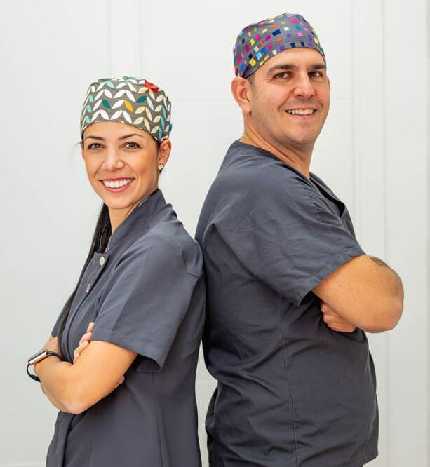 Un hombre y una mujer de pie, espalda con espalda, con los brazos cruzados.