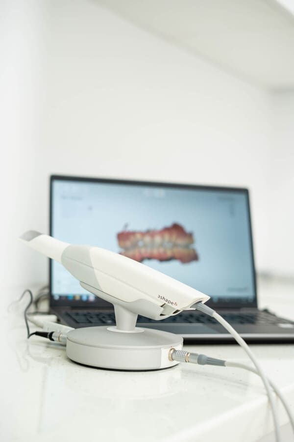 Un escáner dental está sobre una mesa al lado de una computadora portátil.