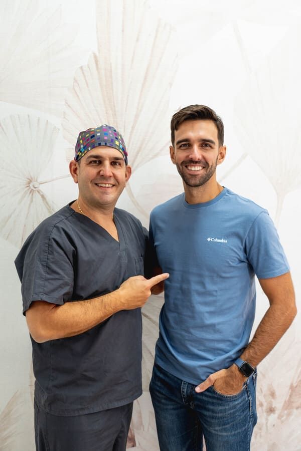 Dos hombres están parados uno al lado del otro y uno está apuntando a la cámara.