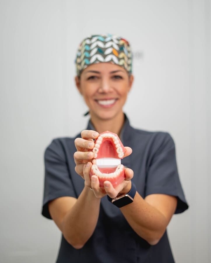 Una mujer sostiene un modelo de dientes en sus manos.