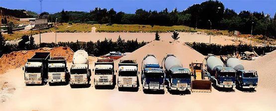Una fila de camiones están estacionados en un camino de tierra